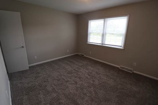 A room with a carpeted floor and a window.