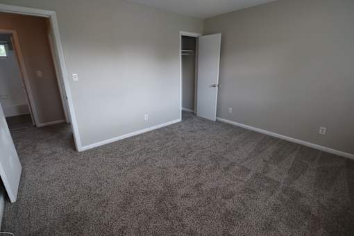 A room with carpeted floor and two doors.