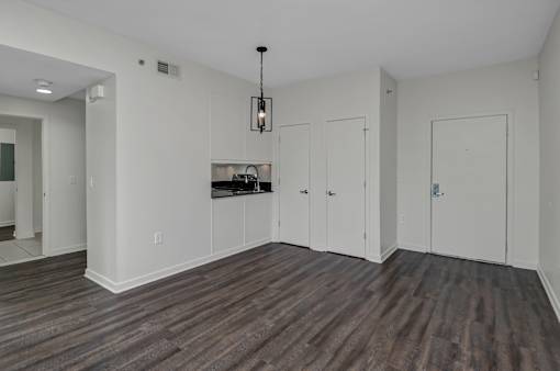 A room with a kitchenette and wood flooring.