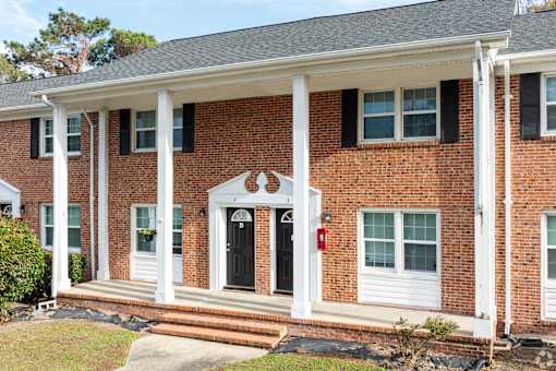 A red brick house with a black door and white columns.
