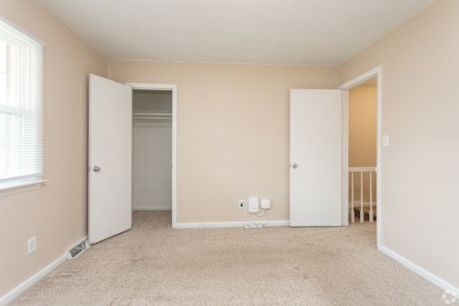 A room with two white doors and a carpeted floor.
