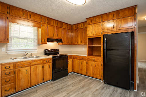 A kitchen with wooden cabinets and a black refrigerator.