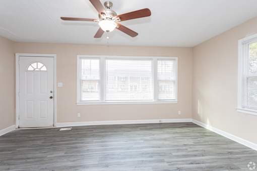 A room with a ceiling fan and a door.