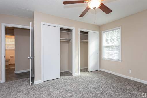 A room with a ceiling fan and carpeted floor.