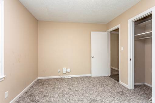 A room with a white door and carpeted floor.