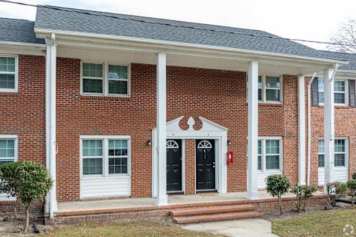 A red brick house with white columns and a black door.