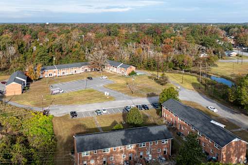 An aerial view of a parking lot and buildings with trees in the background.