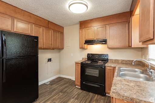 A kitchen with black appliances and wooden cabinets.