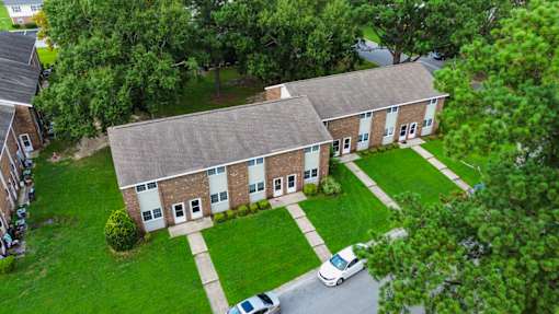 A white car is parked in front of a brick building.
