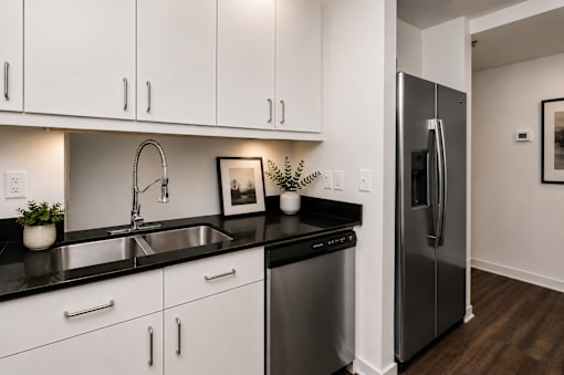 A modern kitchen with white cabinets and black countertops.