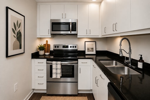 A modern kitchen with white cabinets and black countertops.