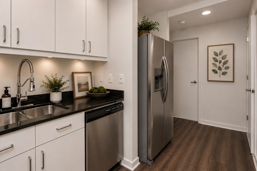 A modern kitchen with a stainless steel refrigerator and white cabinets.