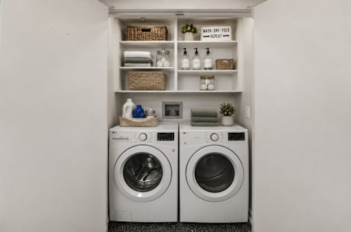 A laundry room with two washing machines and a shelf above them.