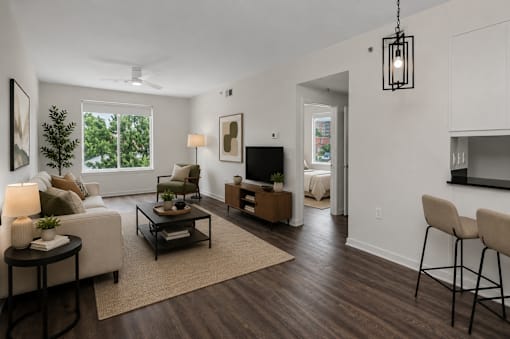 A living room with a white couch, a coffee table, and a television.