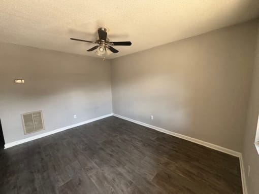 an empty living room with a ceiling fan and wood floors