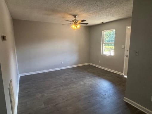 a empty living room with a ceiling fan and a window