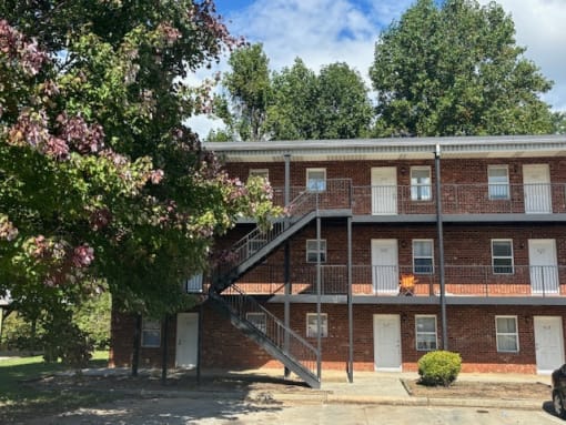 a red brick apartment building with stairs and trees