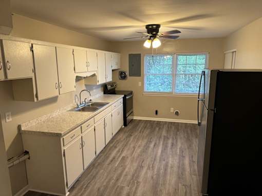 A kitchen with white cabinets and a black refrigerator.