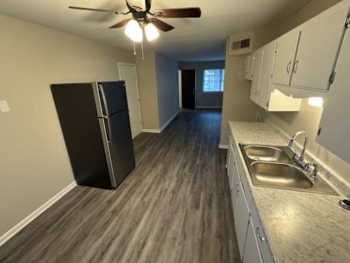 A kitchen with a black fridge and wooden floors.