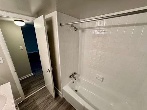 A white bathroom with a white tub and a white sink.