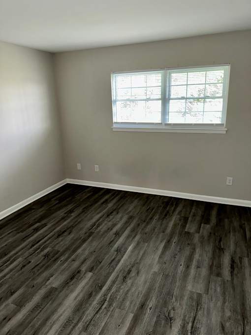 A room with a window and wooden flooring.