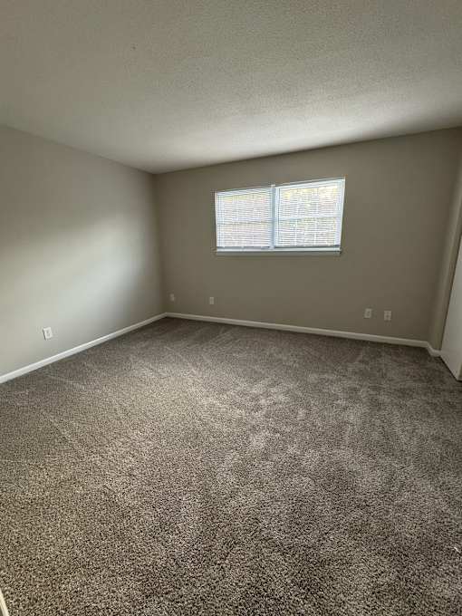 A small window in a corner of a room with a textured wall.