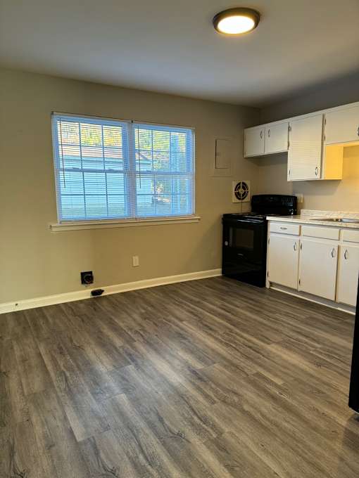 A window with blinds is in a room with a wood panelled wall.