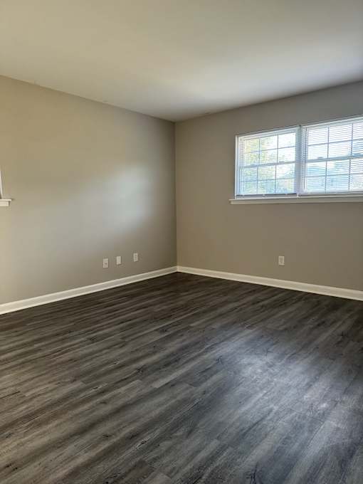 A room with a window and wooden flooring.