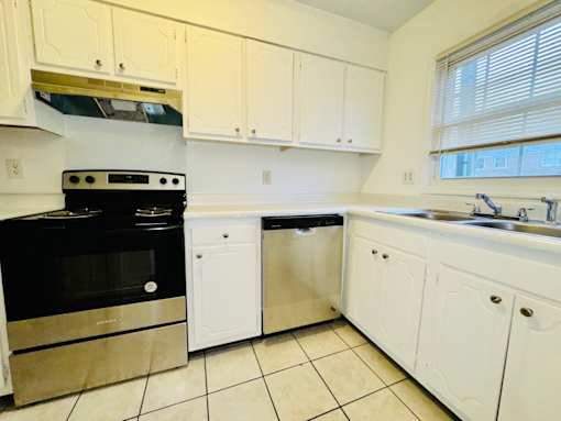 A kitchen with white cabinets and a black stove top oven.