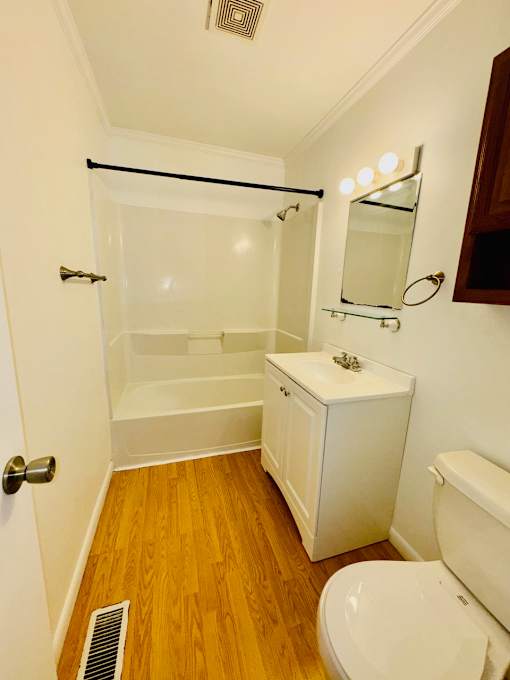 A white bathroom with a toilet, sink, and shower.