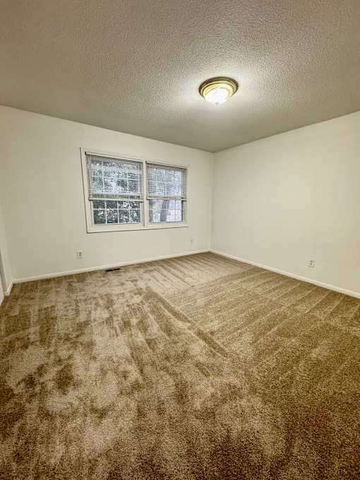 A room with a carpeted floor and a window.