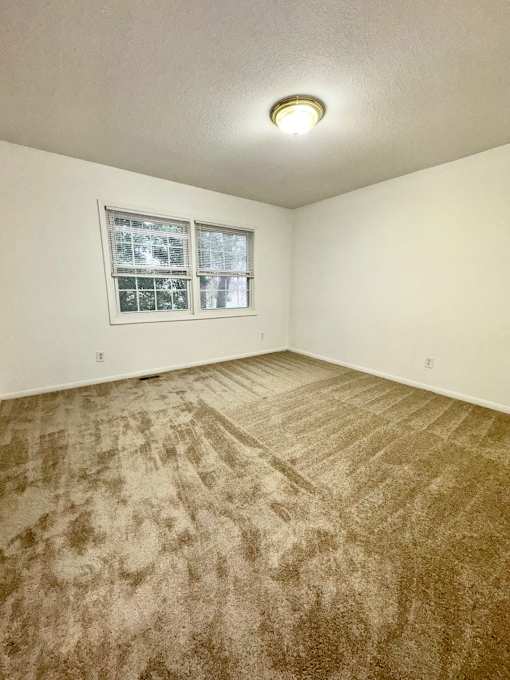 A room with a carpeted floor and a window.