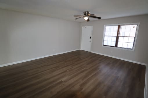 an empty living room with wooden floors and a ceiling fan