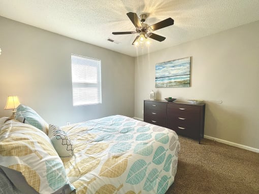 the master bedroom has a large bed and a ceiling fan