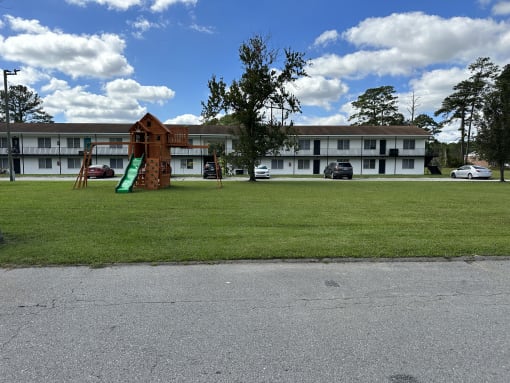 a yard with a swing set in front of an apartment building