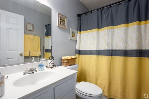 a bathroom with a yellow shower curtain and a white sink and toilet
