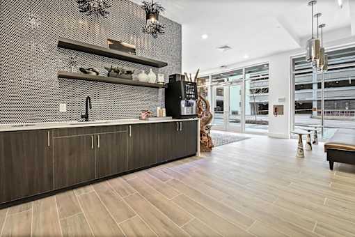 A modern kitchen with a dark wood floor and a black and white tiled backsplash. at The Palms 1101, Columbia, South Carolina