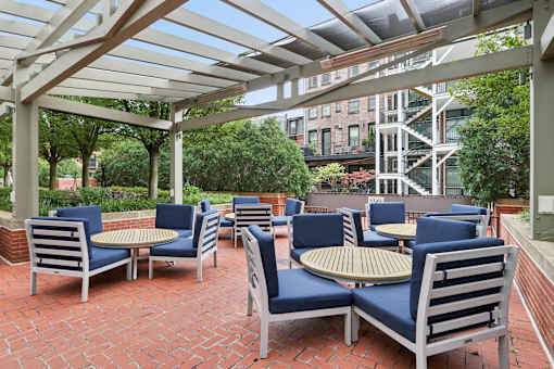 A patio with blue chairs and tables under a white canopy.