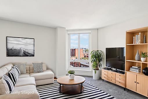 A living room with a white couch, a coffee table, a television, and a bookshelf.