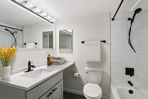A white toilet is in a bathroom with a white sink and a white tub.