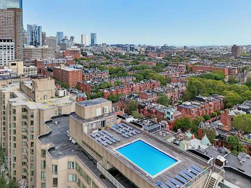 A rooftop pool is surrounded by a cityscape.