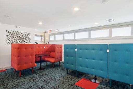 A room with blue and red chairs and a red rug.