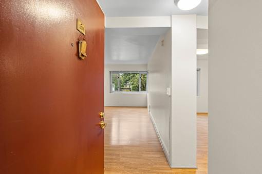 an empty room with a red door and a hallway to a white room