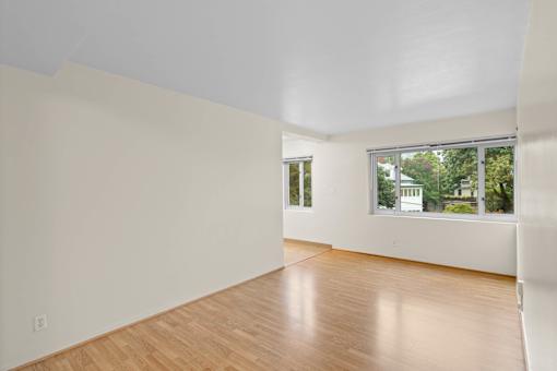 a living room with white walls and a window and wooden floors