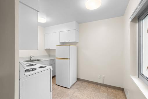 a white kitchen with white appliances and a window