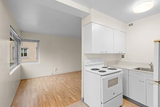 an empty kitchen with white appliances and white cabinets