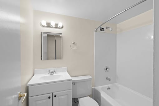 a white bathroom with a white sink and toilet and a tub