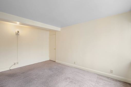 a living room with white walls and a carpet