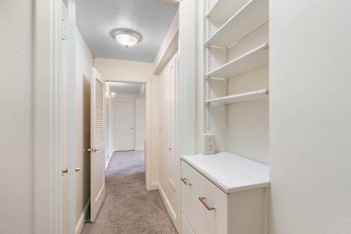 a walk in closet with white cabinets and a white counter