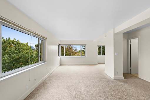 the living room has large windows and a carpeted floor